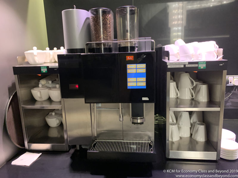 a coffee machine with coffee beans and coffee cups on shelves