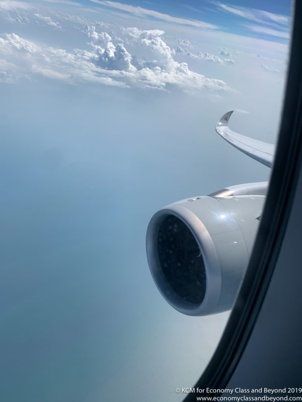 a plane wing and engine above clouds
