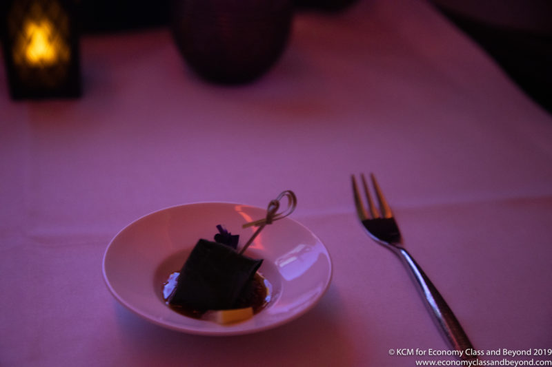 a small plate with a small object on it next to a fork