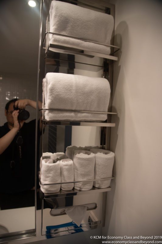 a man taking a picture of a mirror with towels