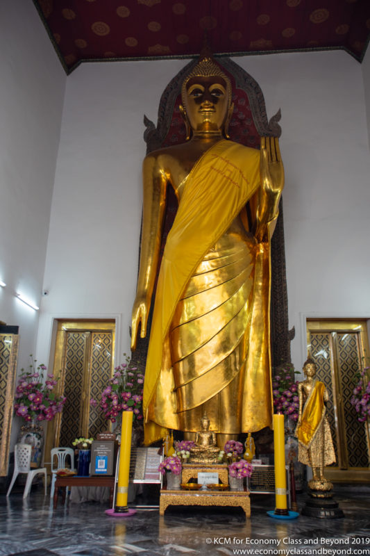 a large gold statue of a person in a room with flowers and candles