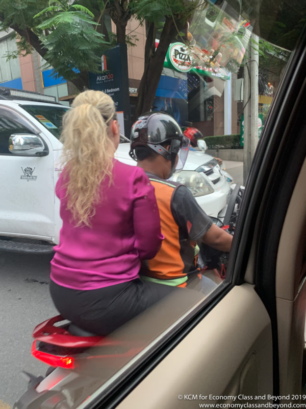 a woman sitting on a motorcycle with a man in helmet