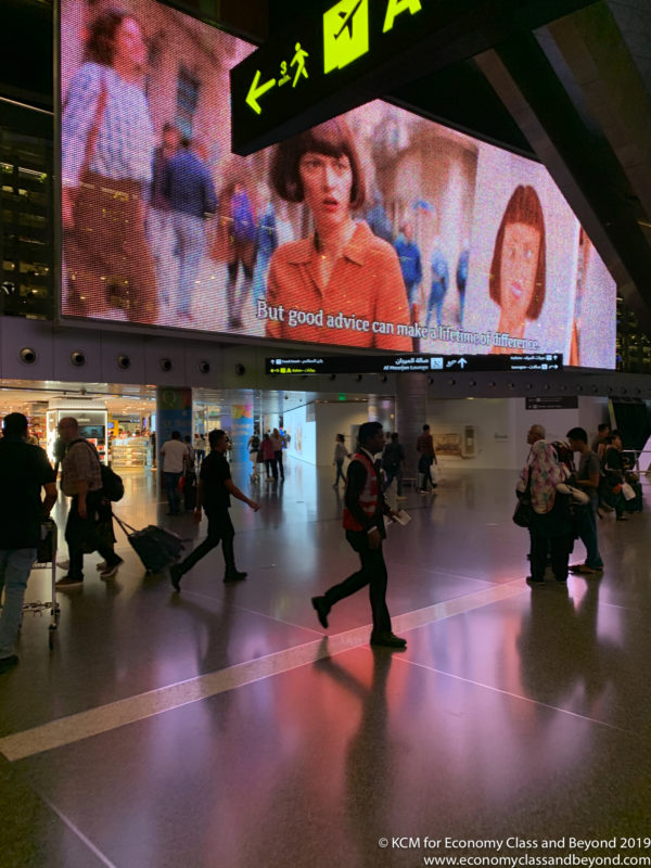 a group of people walking in a large room with a large screen