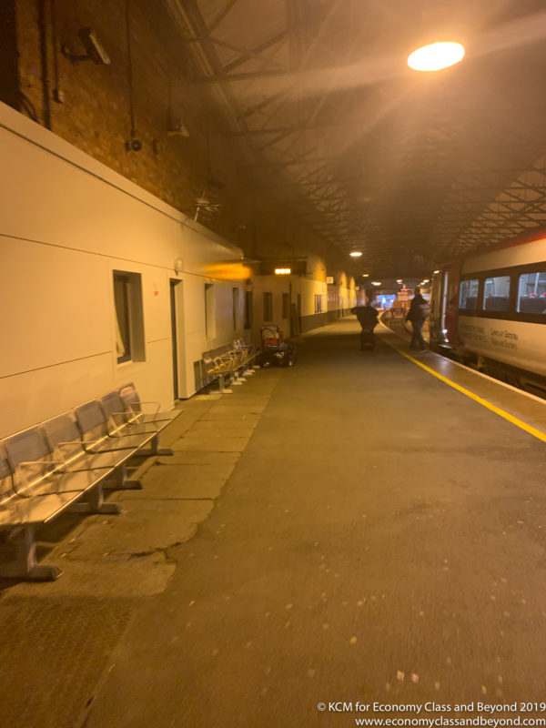 a train station with benches and people walking