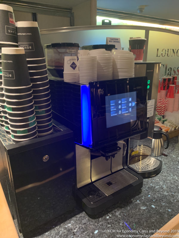 a coffee machine with a screen and stacks of paper cups
