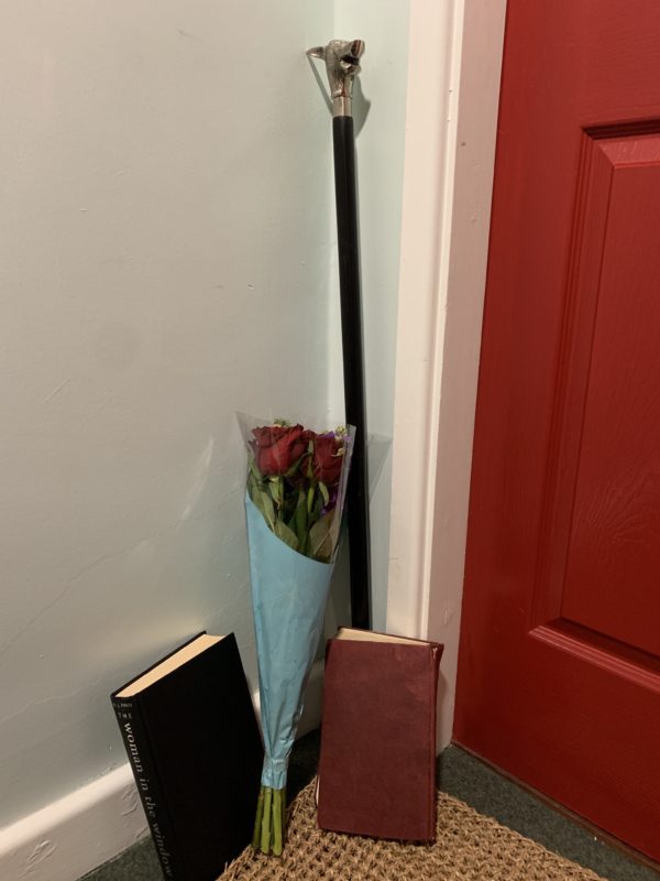 a bouquet of roses and books next to a red door