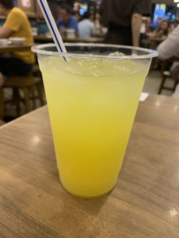a plastic cup with a straw and a yellow drink on a table