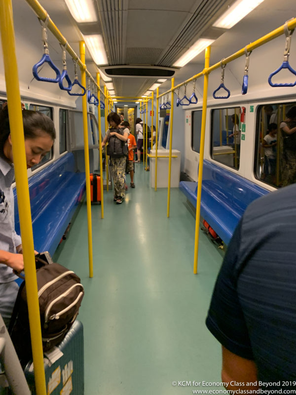people inside a train with blue seats and yellow poles