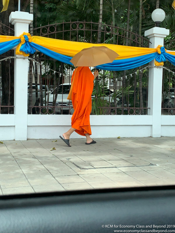a person in an orange robe walking under an umbrella