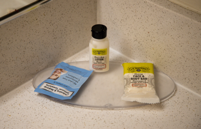a small bottles of body lotion and a packet of condiments on a counter
