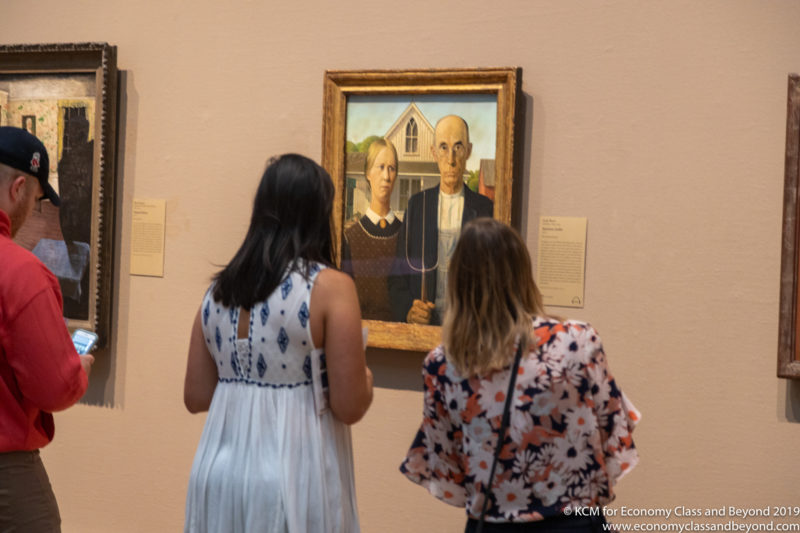 a group of women looking at a painting on a wall