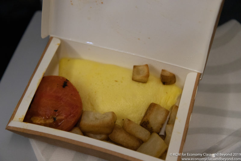 a box of food with a tomato and potatoes