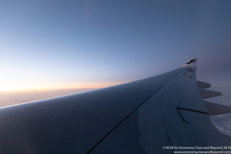 an airplane wing with the sun setting in the background