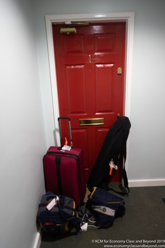 a red door with luggage and a coat on the floor