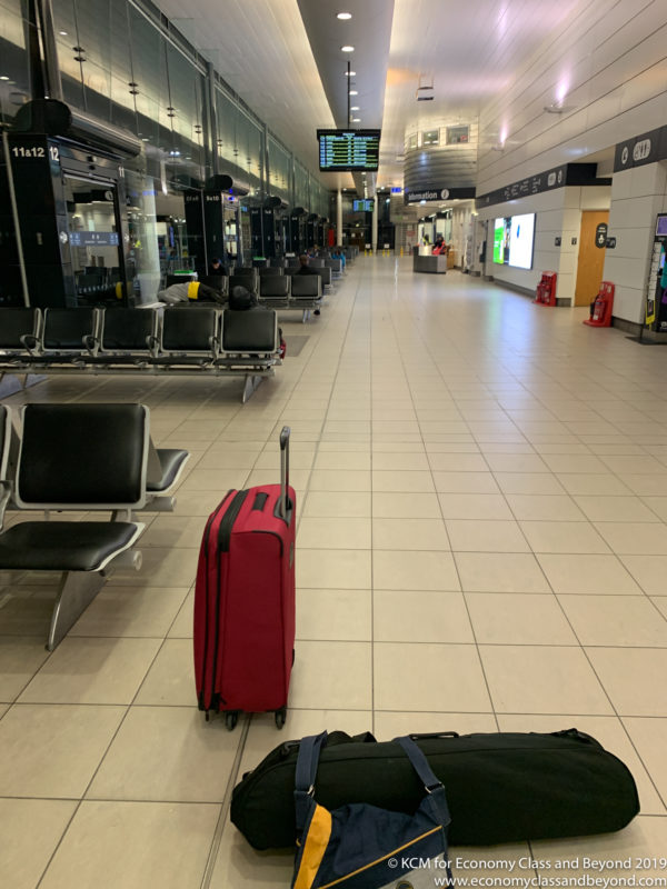 luggage in a terminal with chairs and a sign