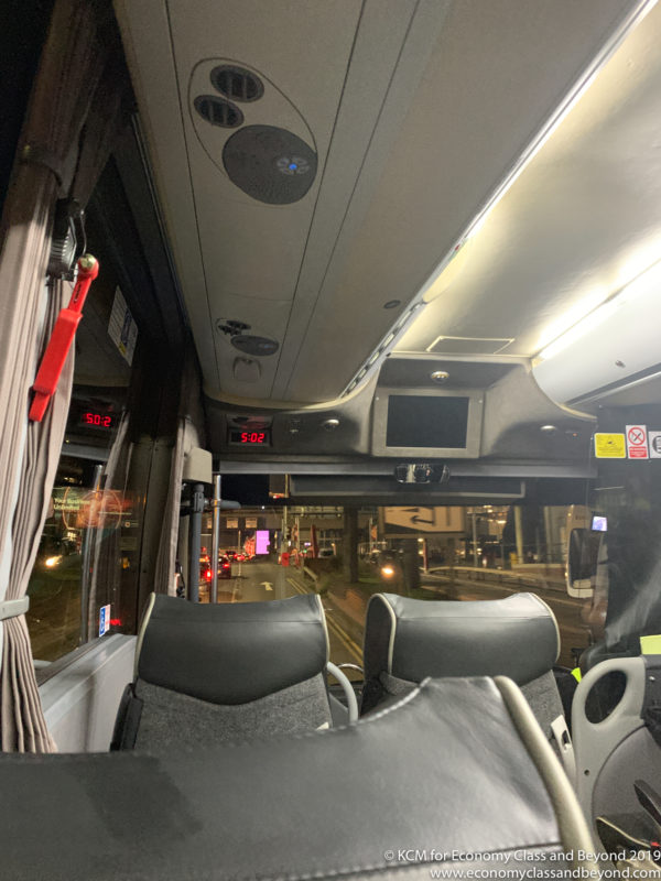 inside a bus with seats and a screen