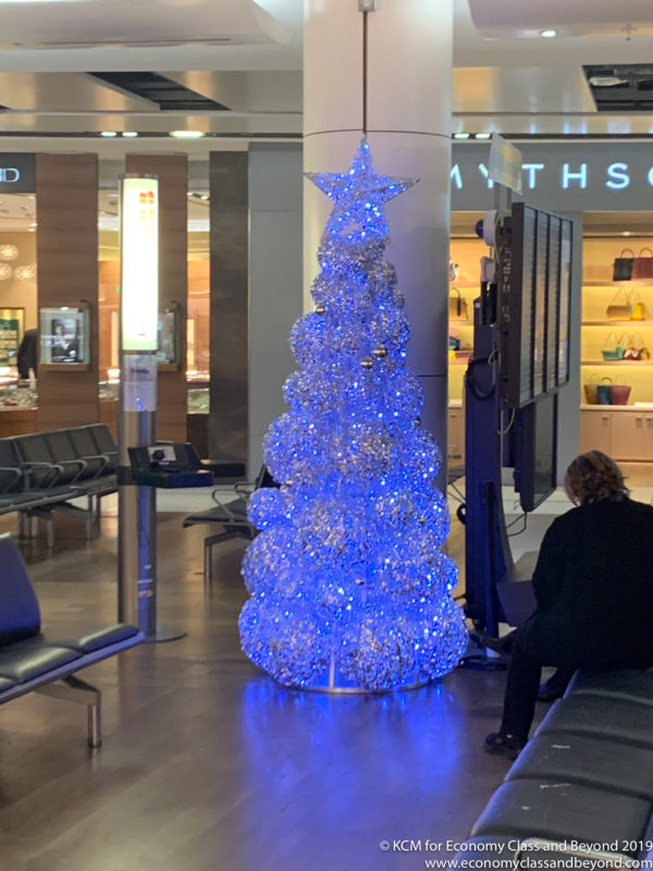 a person sitting on a bench in a building with a christmas tree