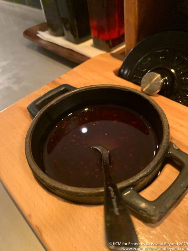 a bowl of sauce with a spoon on a wooden surface