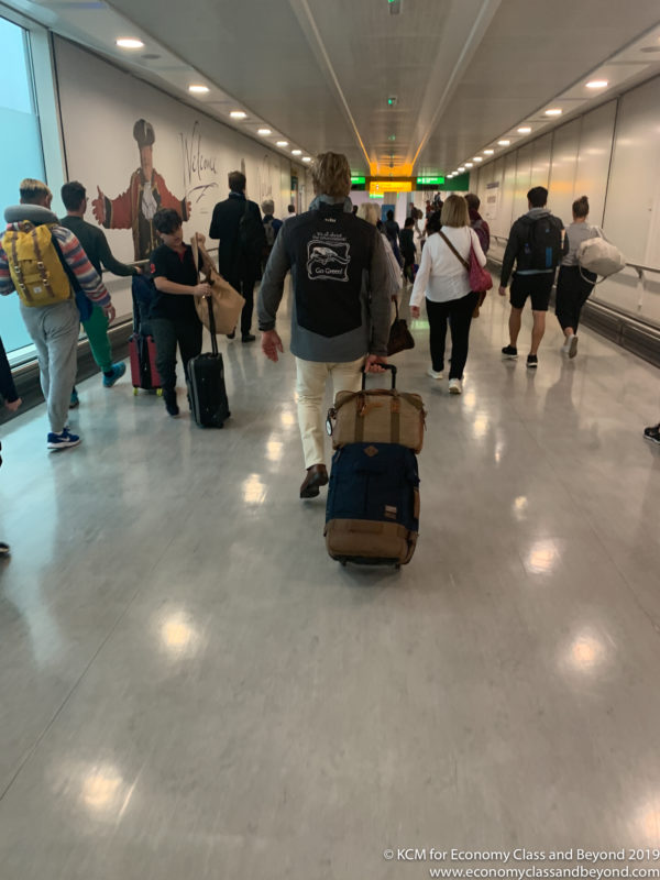 a group of people walking in a hallway with luggage