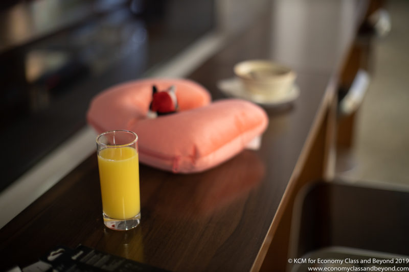 a glass of orange juice next to a pillow