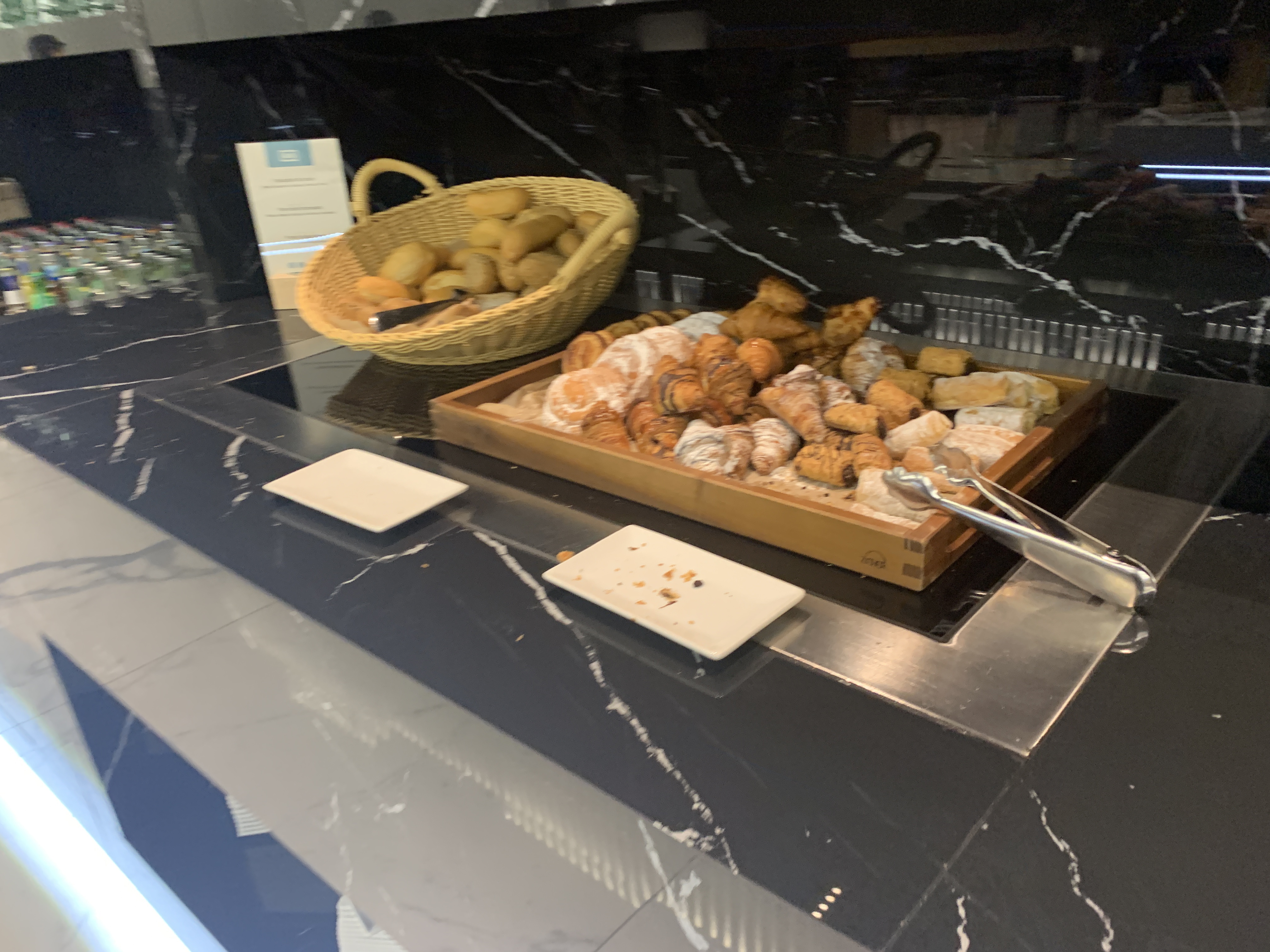 a tray of pastries and a basket of bread on a counter
