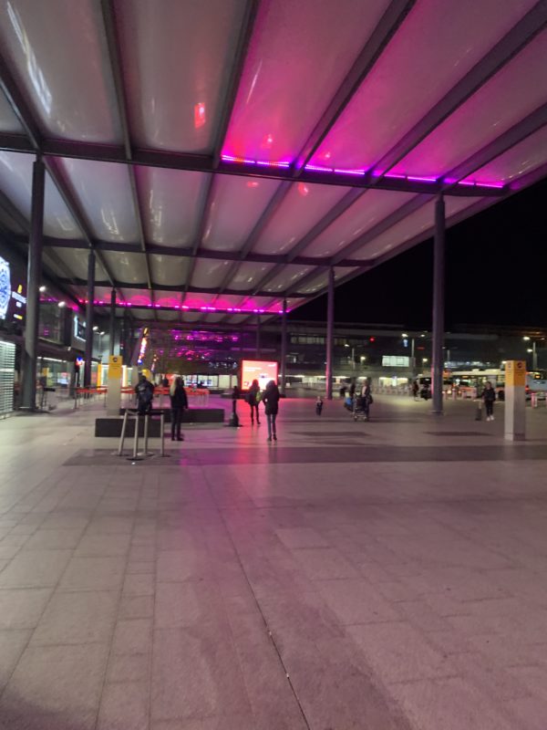 a group of people walking in a large area with purple lights