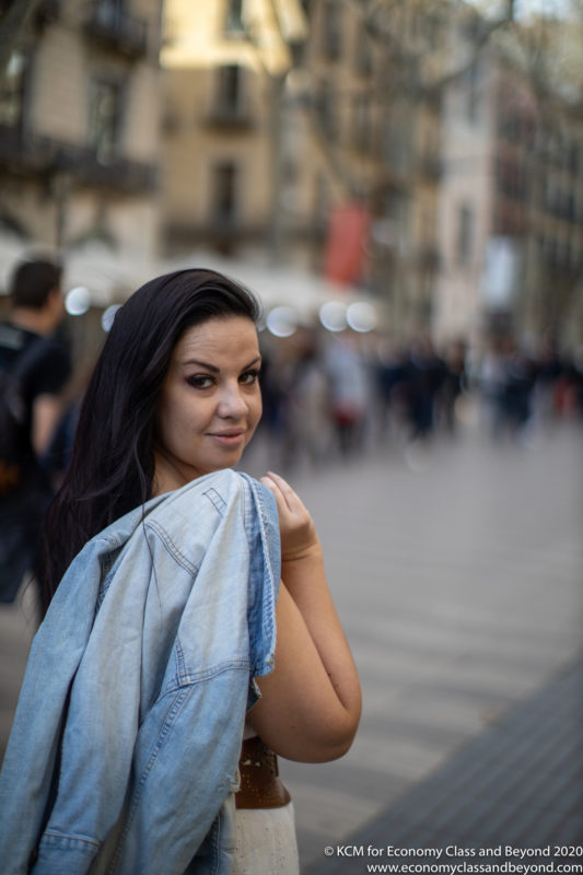 a woman holding a denim jacket over her shoulder