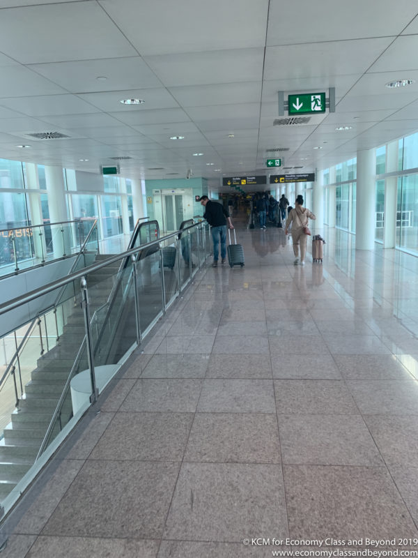 people walking in a building with a staircase and a man and woman with luggage