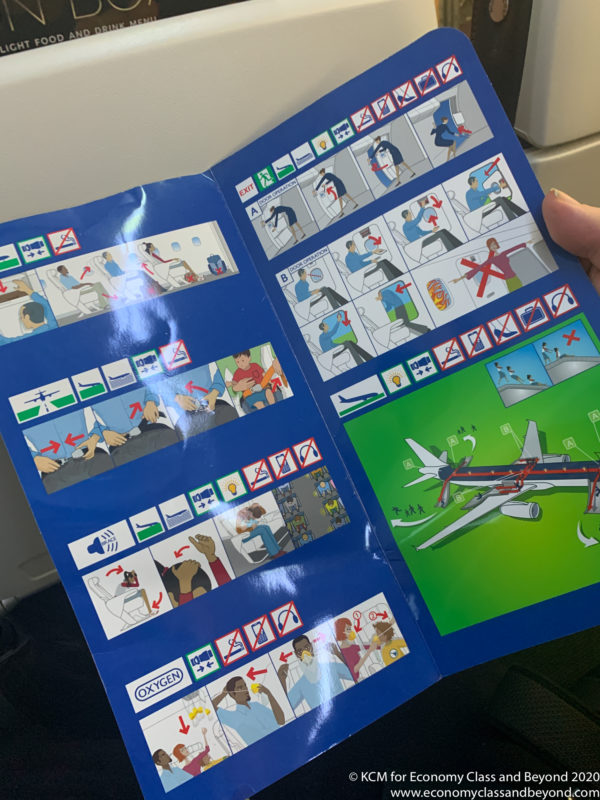 a hand holding a blue book with pictures of people and airplane