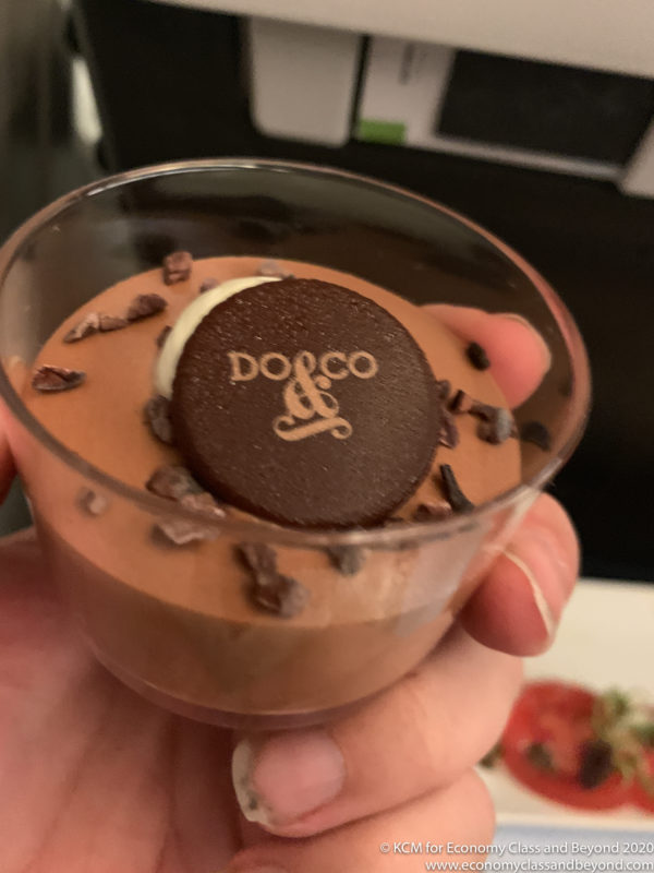 a hand holding a cup of chocolate mousse