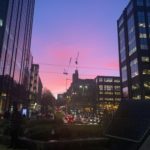 a city street with buildings and a pink sky