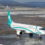 a white and blue airplane on wet runway