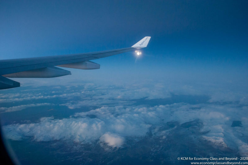 an airplane wing with a bright light above the clouds