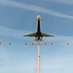 a plane flying over a red light pole