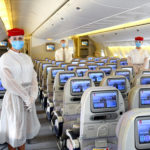 a group of people wearing face masks and standing in an airplane