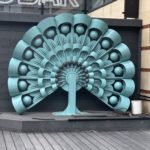 a blue peacock sculpture outside of a building
