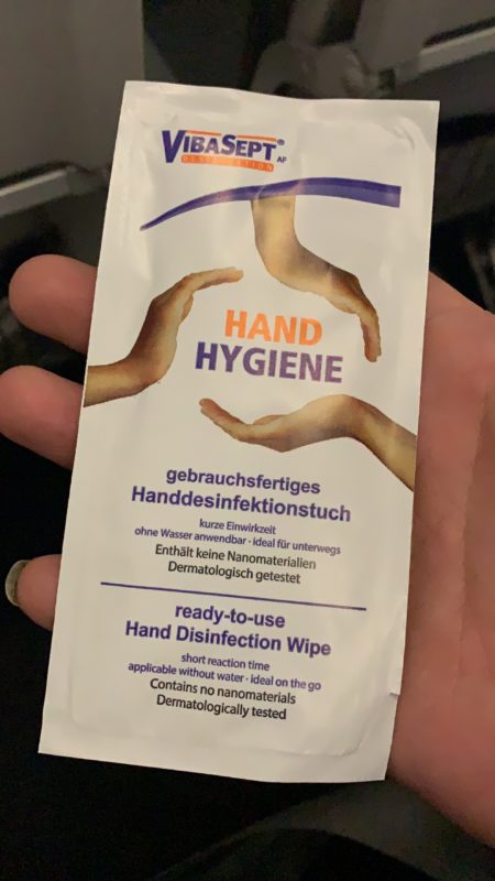 a hand holding a package of hand sanitizer wipes