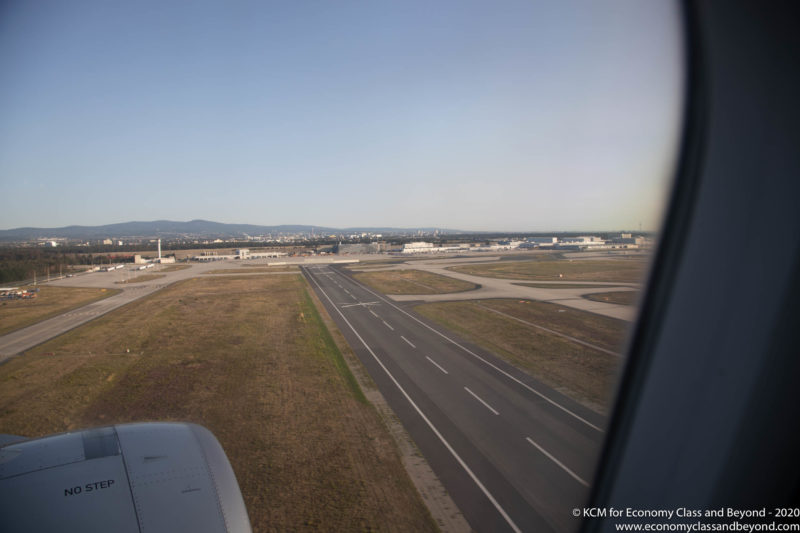 an airplane window with a runway and buildings