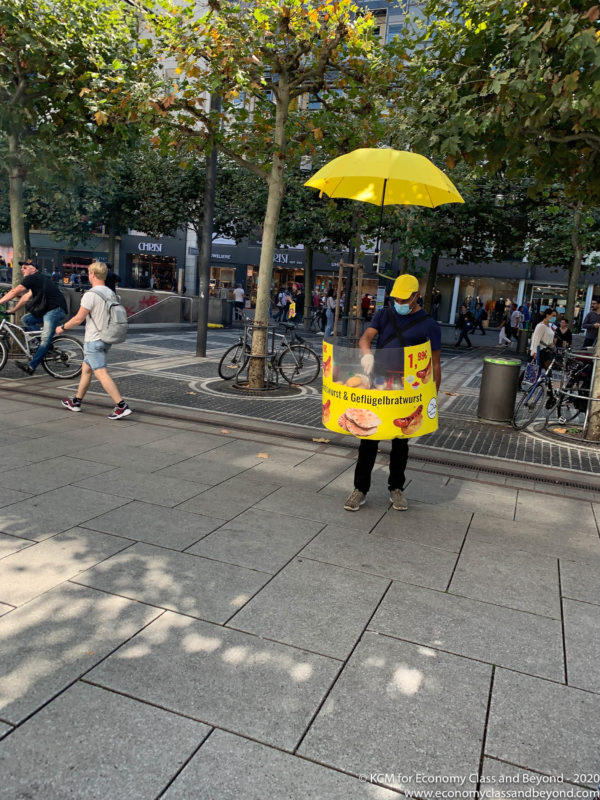 a man wearing a mask and a yellow sign with a yellow umbrella