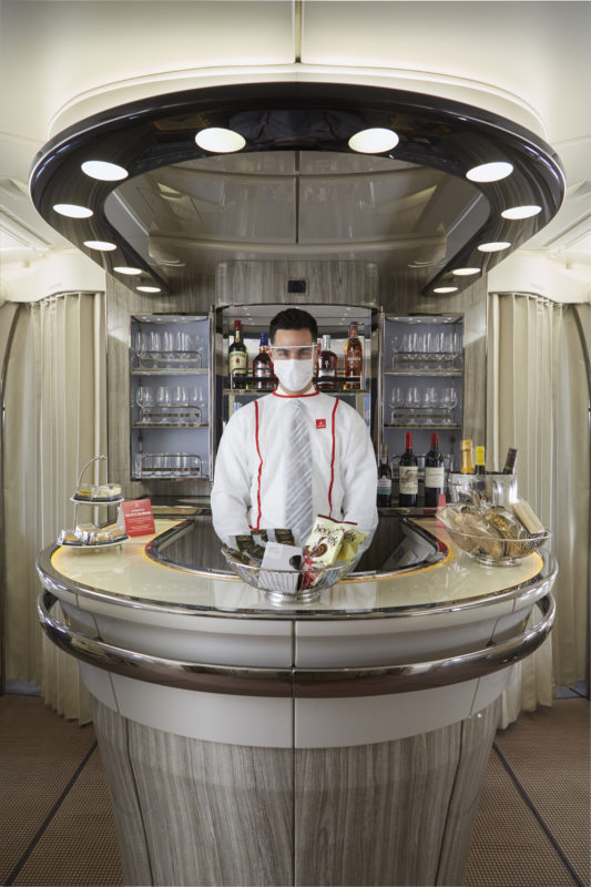 a man wearing a face mask and a white shirt and tie standing behind a counter