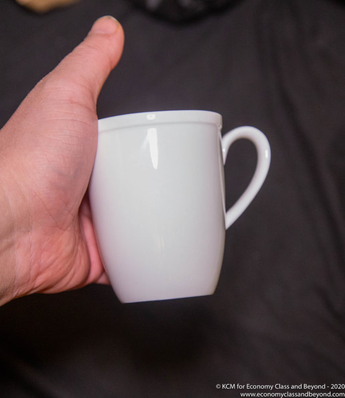 a hand holding a white mug