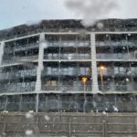 a building with snow falling on the glass