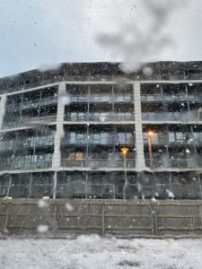 a building with snow falling on the glass