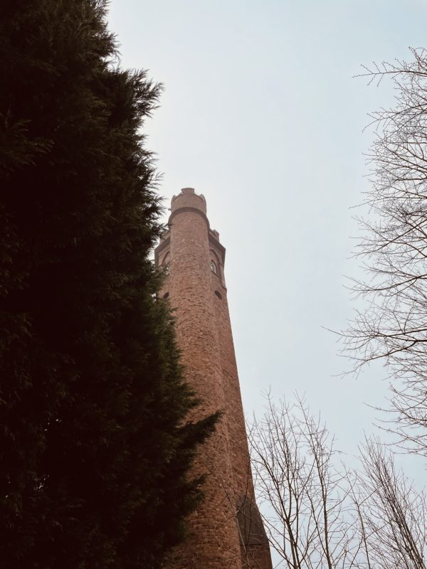 a tall brick tower with a round tower and trees
