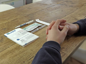 a person's hands on a table with a pen and a paper