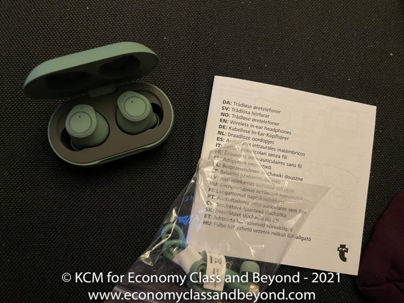 a green earbuds in a case next to a paper