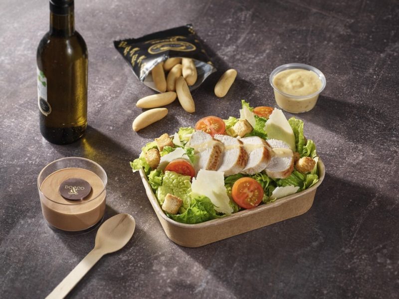 a salad with chicken and sauce in a container