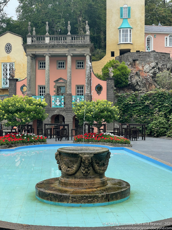 a fountain in a pool with a pink building in the background