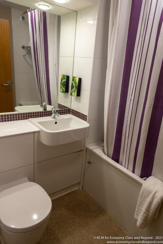 a bathroom with a sink and purple shower curtain