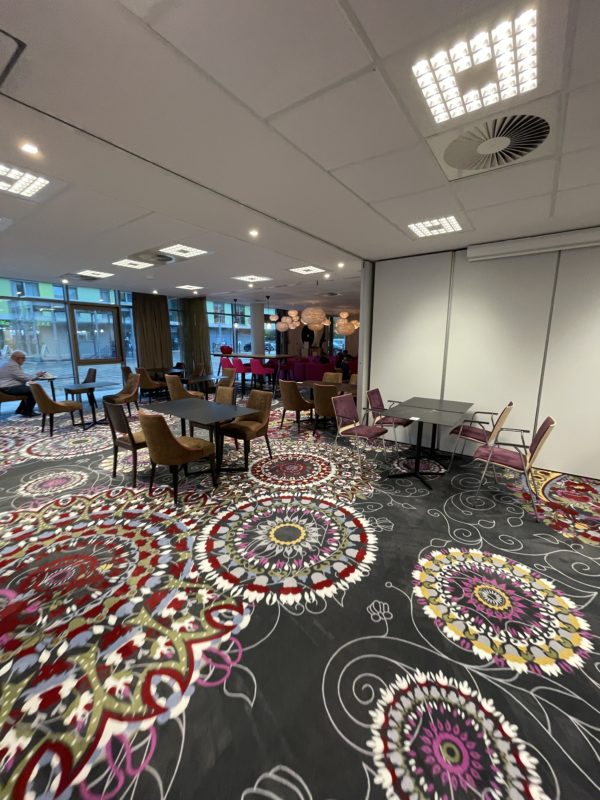 a room with a colorful carpet and tables and chairs
